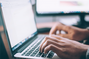 Man sitting down at his laptop, building his own website. 