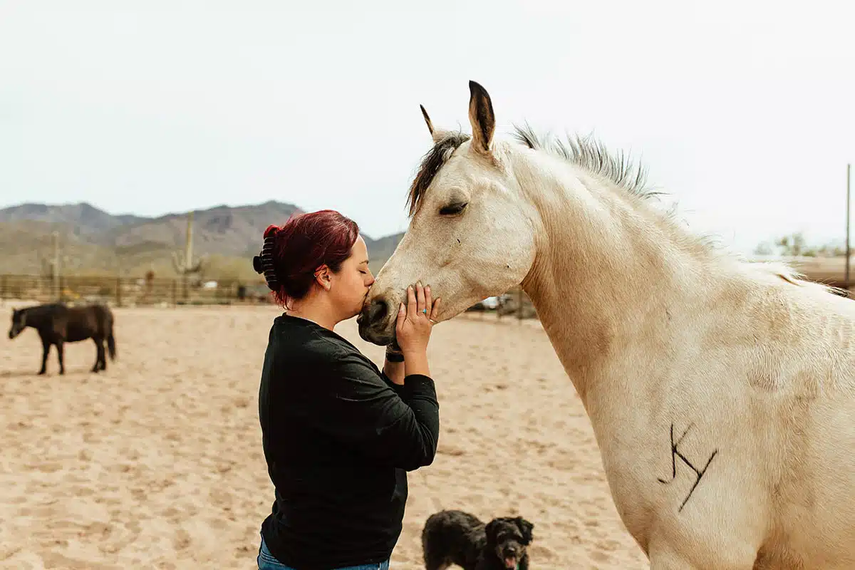 session-in-arena Nonprofit website design for Heartprints Equine Assisted Coaching showing woman connecting with horse during equine therapy session in Cave Creek Arizona